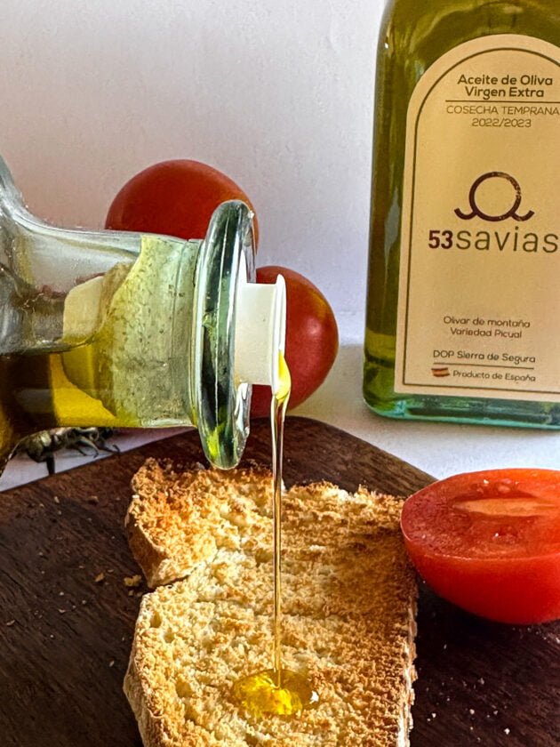 Sirviendo aceite de oliva sobre una tostada y un tomate